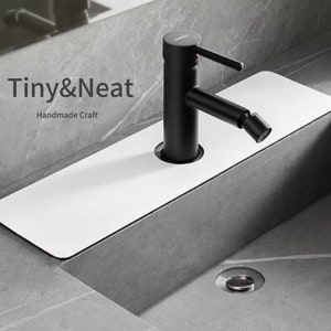 May include: A white rectangular sink drain cover with a black faucet and a grey countertop. The text "Tiny&Neat Handmade Craft" is visible in the image.