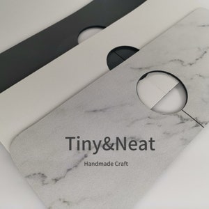 May include: Three white cardboard closet hanger dividers with a round hole in the center. The top divider has a marble pattern and the text "Tiny&Neat Handmade Craft".