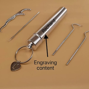 May include: A silver-coloured metal cylindrical case with a keyring and heart-shaped charm, accompanied by four dental tools. The case features the engraved name Rechard and an arrow pointing to the text with the label Engraving content.