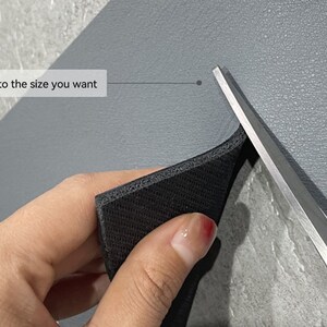May include: A hand holds a black foam sheet with a pair of scissors cutting it. The text "Can be cut to the size you want" is visible in the image.