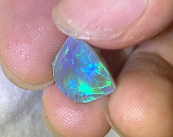 May include: A teardrop-shaped opal gemstone with a blue, green, and white iridescent sheen.