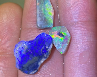 May include: Three rough-cut opals, one blue, one green, and one iridescent, with a rainbow of colors.