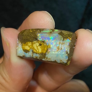Könnte beinhalten: Ein Stück roher Opal mit einer braunen Matrix und irisierenden Farbschimmern.