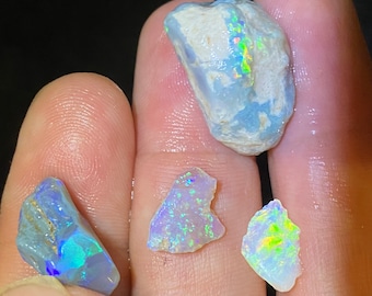 May include: Four pieces of rough opal, one large and three smaller, with iridescent colors of blue, green, and yellow.