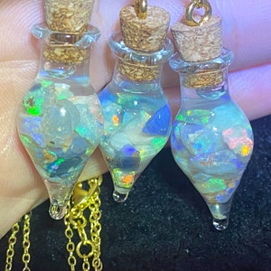 May include: Three small glass bottles with cork stoppers and gold chains. Each bottle is filled with iridescent opal stones.
