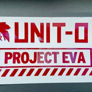 May include: Red and white sticker with the text "UNIT-01 PROJECT EVA" in a red box with red and white stripes. The sticker also features a red leaf with the text "NERV" in white.