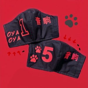 May include: Two black fabric face masks with red paw prints and numbers. The top mask has the number "1" and the text "OYA OYA" and "青 駒". The bottom mask has the number "5" and the text "青 駒".