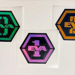 May include: Three hexagonal stickers with the text "EVA" and a number inside. The stickers are green, purple, and orange.