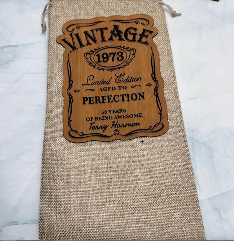 May include: A brown wooden sign with the text "Vintage 1973 Limited Edition Aged to Perfection 50 Years of Being Awesome Terry Harmon" in black lettering.
