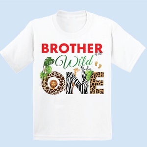 May include: White t-shirt with the text "BROTHER of the Wild ONE" in red and green. The word "ONE" is decorated with animal prints and illustrations of a lion, giraffe, and zebra. Includes small footprints.