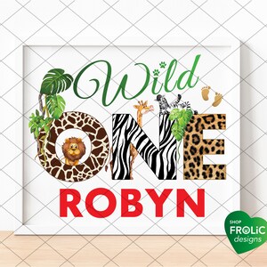 May include: A framed print with the words "Wild One Robyn" in green and red. The letters are decorated with animal prints and illustrations of a lion, giraffe, and zebra. Green leaves and paw prints add to the jungle theme.