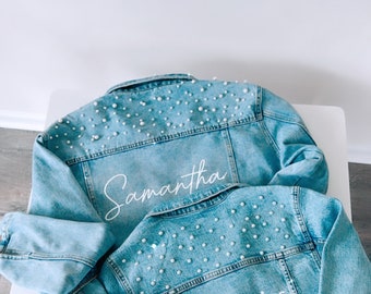 Könnte beinhalten: Zwei Jeansjacken mit Perlenbesatz. Die größere Jacke hat den Namen "Samantha" auf dem Rücken. Die kleinere Jacke hat den Namen "Olivia" auf dem Rücken.