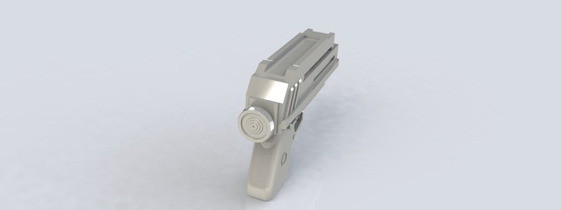 K&ouml;nnte beinhalten: Eine silberfarbene, futuristisch aussehende Pistole mit einem zylindrischen Bauteil an der Seite und einer geriffelten Oberseite. Die Waffe ist vor einem schlichten wei&szlig;en Hintergrund platziert.