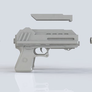 K&ouml;nnte beinhalten: Eine zerlegte, hellgraue Pistole mit futuristischem Design. Die Komponenten sind um den Hauptk&ouml;rper angeordnet, darunter ein Oberteil, ein Zylinder und ein Stift. Die Pistole verf&uuml;gt &uuml;ber einen Abzug und einen Griff.