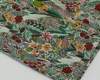 May include: A folded fabric with a botanical pattern. The design features a cream background with a dense arrangement of green leaves, red and yellow flowers, and brown accents. The fabric is likely cotton or a similar material.