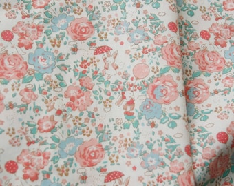 May include: A white fabric featuring a repeating pattern of pink and blue roses, small green leaves, and white rabbits. Some rabbits are depicted holding red umbrellas or pink balloons, interspersed with tiny bees and small brown floral accents.