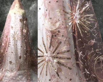 May include: Pink sheer fabric with gold sequins in a starburst pattern. The fabric is embroidered with gold thread and has a delicate, sparkly look.