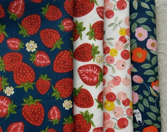 May include: Four vertical strips of fabric featuring distinct patterns. The first is dark blue with red strawberries and white flowers. The second is white with red strawberries. The third is white with small red and yellow berries. The fourth is dark blue with flowers and a small cat.