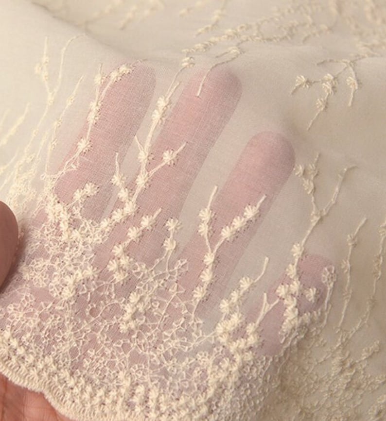 Peut inclure: Tissu blanc ivoire transparent avec de d&eacute;licats motifs floraux brod&eacute;s. Le tissu est doux, a&eacute;r&eacute; et parfait pour cr&eacute;er des v&ecirc;tements l&eacute;gers.