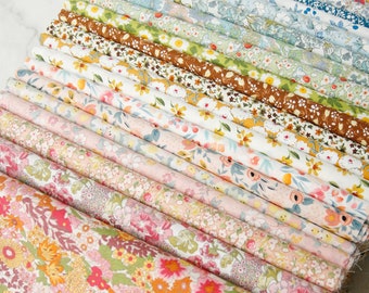 May include: A collection of rolled fabric bolts, each displaying a unique floral pattern. The fabrics feature a variety of colors, including pink, blue, green, and yellow, with intricate designs of flowers and leaves. The bolts are arranged in a diagonal pattern.