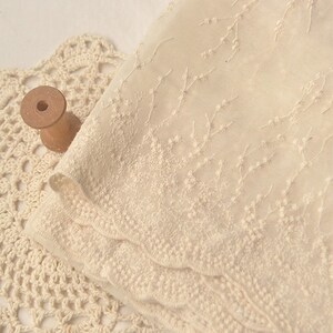 Peut inclure: Tissu transparent de couleur cr&egrave;me avec un motif de broderie florale d&eacute;licate. Le tissu a un bord festonn&eacute;.