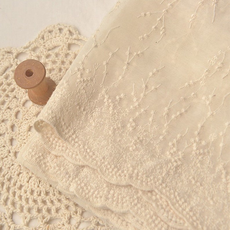 Peut inclure: Tissu transparent de couleur cr&egrave;me avec un motif de broderie florale d&eacute;licate. Le tissu a un bord festonn&eacute;.