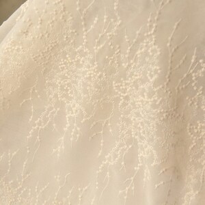 Peut inclure: Tissu blanc transparent avec un motif d&eacute;licat brod&eacute; de petites fleurs blanches et de branches.
