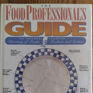 May include: The Food Professional's Guide book cover. The title is in large orange and gold letters. The James Beard Foundation directory of people, products, and services. A white plate with a blue and white checkered border is in the center of the cover.