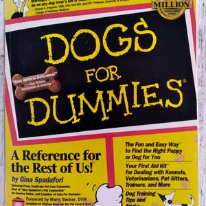 May include: A book titled "Dogs For Dummies" with a yellow and black cover. The cover has large yellow text on a black background. The book provides information on dog training, puppy care, and other related topics. It is a reference guide for dog owners.