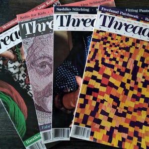 Könnte beinhalten: Eine Sammlung von Ausgaben des Magazins "Threads" mit verschiedenen Titeln wie "Tailor's Suit", "Knits for Kids" und "Freehand Patchwork". Die Zeitschriften zeigen farbenfrohe Designs und Texte, die sich auf Nähen und Textilhandwerk beziehen.