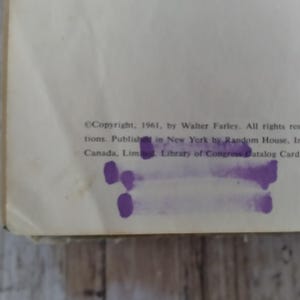 Pu&ograve; includere: Primo piano di una pagina di libro con testo. Il testo include informazioni sul copyright del 1961 di Walter Farley, pubblicato a New York da Random House. La pagina presenta segni viola ed &egrave; leggermente ingiallita.