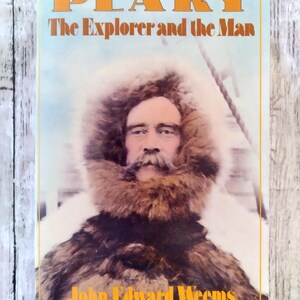 Puede incluir: Portada de libro con el título "PEARY The Explorer and the Man" en naranja. La portada muestra un retrato de un hombre con una capucha ribeteada de piel. También se muestra el nombre del autor, John Edward Weems, y un prólogo de Sir Edmund Hillary.