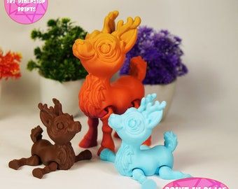 May include: Three 3D printed reindeer figurines in different sizes and colors. The largest reindeer is orange, the middle reindeer is blue, and the smallest reindeer is brown. The reindeer are all in a playful pose, with their legs bent and their heads tilted. The text "PRINT IN PLACE NO SUPPORTS" is visible in the bottom right corner of the image.