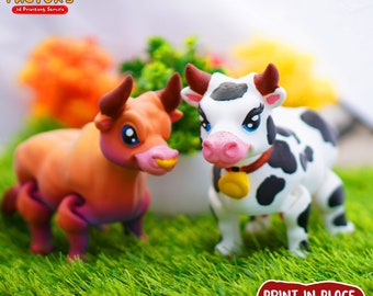 May include: Two 3D printed cartoon animal figurines, a brown bull and a black and white cow, standing on a green grassy surface. The bull has a pink nose and yellow horns. The cow has a pink nose and a bell around its neck. The text "PRINT.IN.PLACE NO SUPPORTS" is printed on a red background in the lower right corner of the image.