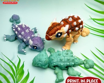 May include: Three 3D printed Ankylosaurus dinosaur models in different colors: purple, green, and brown. The dinosaurs are posed in a playful manner. The text "PRINT.IN.PLACE NO SUPPORTS" is printed on the bottom right corner of the image.