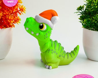 May include: A green dinosaur figurine wearing a red and white Santa hat. The dinosaur is sitting on a white surface. The text "No Supports" is visible in the lower right corner of the image.