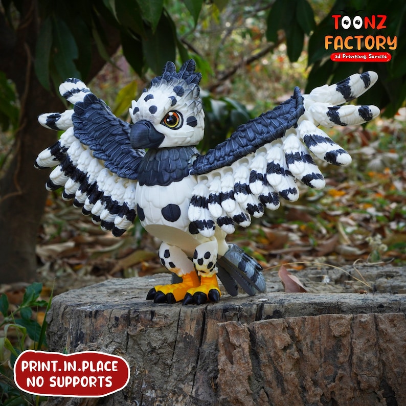 May include: A 3D-printed figurine of a stylized bird with outstretched wings, perched on a tree stump. The bird features a black and white color scheme with yellow and black feet. The image includes the text "TOONZ FACTORY 3D Printing Service" and "PRINT.IN.PLACE NO SUPPORTS."