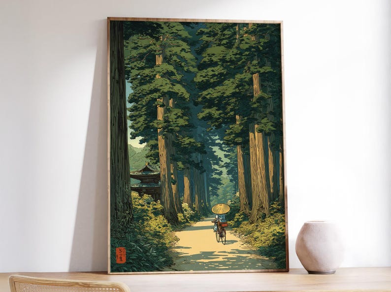 Japanese inspired art print of an elderly lady cycling through a lush green forest, traditional style poster with calming nature tones, shown framed and displayed in a white room