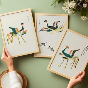 May include: Three rectangular wall art prints in light wood frames, each featuring detailed illustrations of colorful birds with long tail feathers and black calligraphy text on a white background, displayed together in a collection.