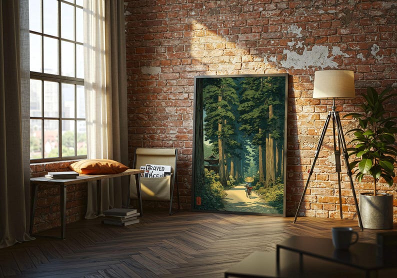 以下が含まれることがあります： 高い木々の森の中の小道を描いた、額入りのアートプリント。アートワークは、レンガの壁、カーテン付きの窓、木の床がある部屋に展示されています。フロアランプと鉢植えの植物も表示されています。