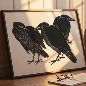 Peut inclure: Impression artistique encadrée en noir et blanc représentant trois corbeaux. Les oiseaux sont dessinés avec des détails texturés sur fond clair. L'œuvre est présentée dans un cadre sombre, appuyée contre un mur.