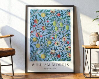May include: A framed wall art print featuring a William Morris Pomegranate pattern with green leaves, yellow and red fruits, and small flowers on a light blue background. The text WILLIAM MORRIS POMEGRANATE is printed in black at the bottom.