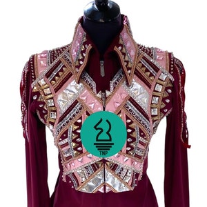 May include: A maroon show shirt with a pink, gold, and silver geometric design. The shirt has a zipper closure and long sleeves with decorative cuffs. The shirt is embellished with rhinestones.
