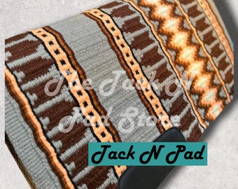 Puede incluir: Un cojín de silla de montar gris, marrón y naranja con un patrón geométrico. El cojín tiene una solapa de cuero negro con el texto "Jack N Pad" impreso en ella.