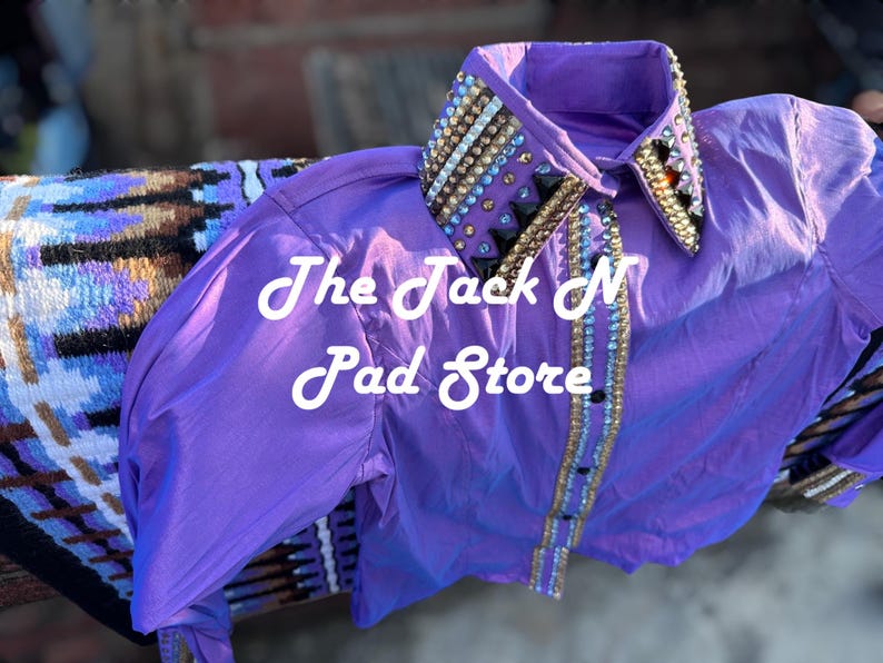 May include: A bright purple shirt with a decorated collar. The collar and front of the shirt are adorned with gold, silver, and black embellishments. The text "The Jack N Pad Store" is visible on the shirt.