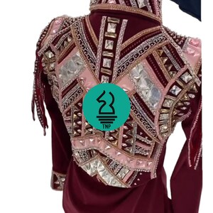May include: Burgundy show shirt with long sleeves and a pink and gold geometric design with rhinestones and fringe. The shirt has a high collar and a TNP logo on the back.
