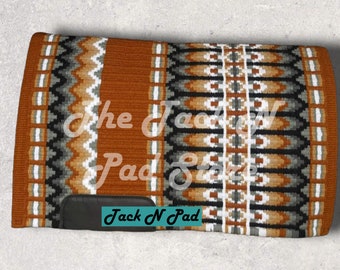 Puede incluir: Un cojín de silla de montar marrón, negro, blanco y gris con un patrón geométrico. El cojín tiene un parche de cuero negro con el texto "Jack N Pad" en blanco.