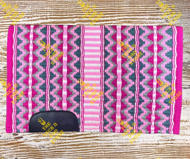 May include: Pink, gray, and white woven saddle pad with a black leather patch that says "The Tack N Store".