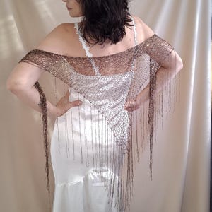 Hand-knitted triangle shawl with sequins. A versatile knitted scarf, cape, or belt accessory.