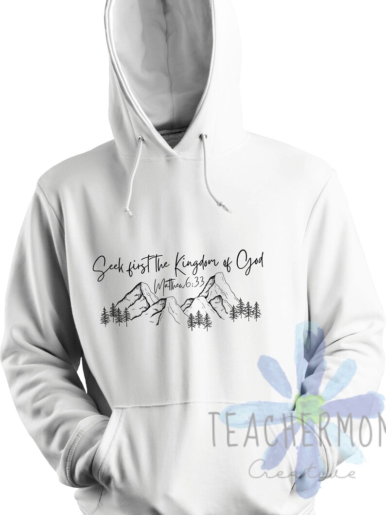 May include: White hoodie with a black graphic of mountains and trees. The text "Seek first the Kingdom of God" is written above the mountains. The text "Matthew 6:33" is written below the mountains.